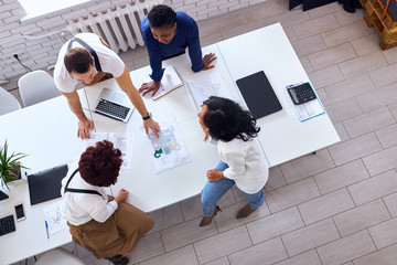 Business team consisted of multiethnic people, gathered in office to discuss new project