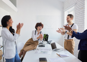 Multiethnic team of happy people applauding at international conference after successful solution