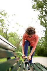 woman runner tying shoelace outdoor on bench