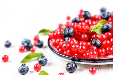 Fresh blueberries and red currants with mint leaves in a wooden bowl on burlap. Diet food, vegan berries