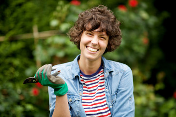 smiling female gardener standing with scissors in garden