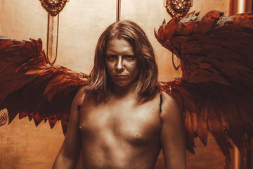 halloween make up. boy ready for party. man is covered in gold paint and poses with large angel...