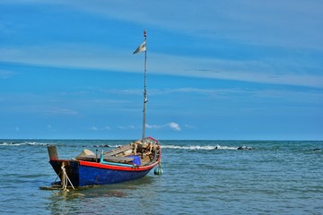 Fototapeta premium Fishing boat floating in the sea with blue sky.