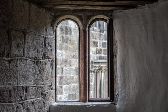 Detailed view of the interior, looking out of a medieval building. The restored stonework and arched windows are evident in this popular attraction.