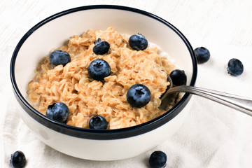 Oatmeal with fresh blueberries. Diet food - oatmeal porridge in a plate with a spoon.