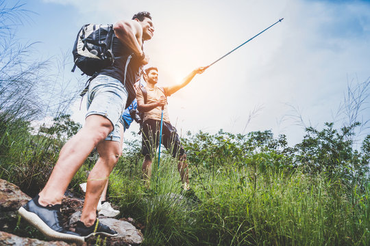 Group friends hiking walking in wild forest and stand for relax on summer holiday vacation time, man point by trekking ploes for looking to destination.
