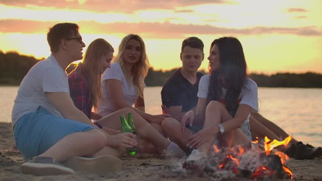 Young people are enjoying warm summer evening on the sand beach