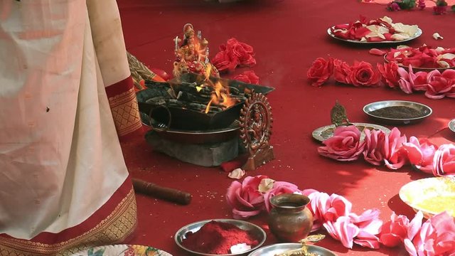 Indian wedding ceremony, decorations for traditional ethnic rituals for marriage, fire burning, flowers and statuettes of the deity on red carpet