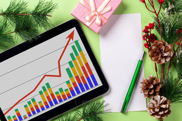 A tablet with a business graph on the desktop. Christmas decorations.