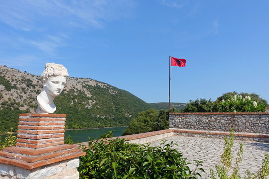 Flag of Albania over the Byzantine fortress and the ruins of the ancient Greek city of Butring
