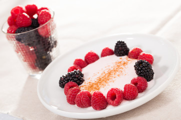 breakfast of raspberries and blackberries with yogurt on table