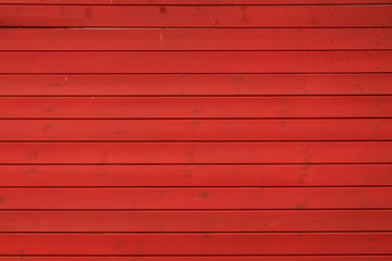 Fragment der Wand eines roten Holzhauses. Die Wand besteht aus neuen Brettern. Die Bretter sind horizontal angeordnet. Hintergrund. Textur.