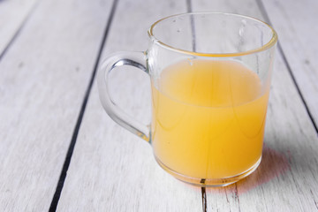 Half cup of orange juice on a white wooden background