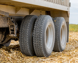 Large grain truck with tandem axle dual wheels with retread rubber tires parked in farm field...