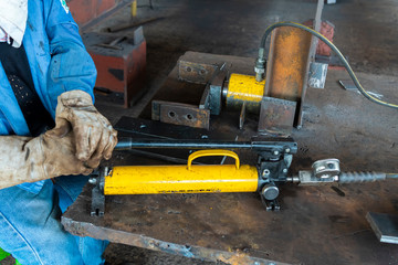 Workers are using hydraulic jacks. bending steel plate in industrial factory.(Focus on bending steel plate point)
