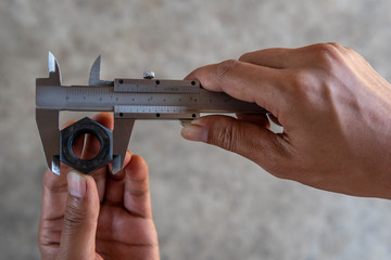 Using Vernier caliper to measure the dimensions of the nut.