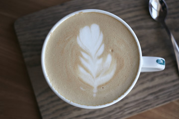 Cappuccino with tulip latte art on rustic wood table in cafe.