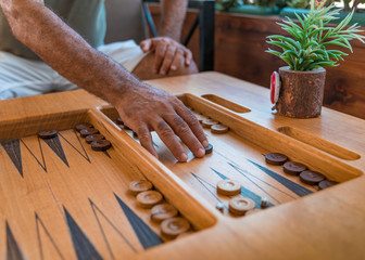 Male playing a traditional oriental board game of backgammon in coffee room. Men's hands moving chips