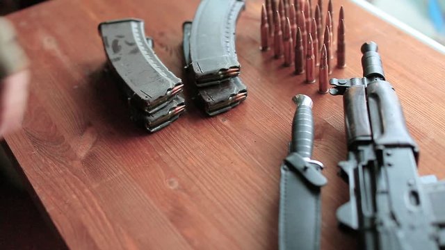 The hand of a soldier or a terrorist puts ammo on the table