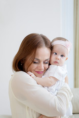 Affectionate woman embracing her baby on couch