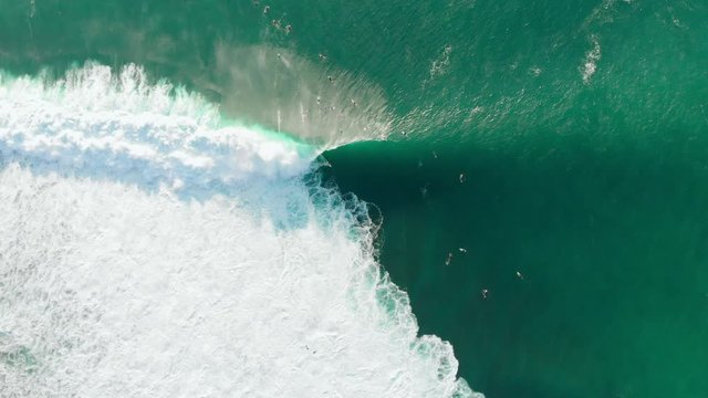 Aerial view with surfers and barrel wave in ocean. Top view. Surfing at waves