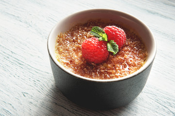  Creme brulee or catalana  with raspberries . Traditional French, Spanish and Italian vanilla cream dessert with caramelized brown sugar. Delicious,  tasty, sweet dish. Copy space. Selective focus