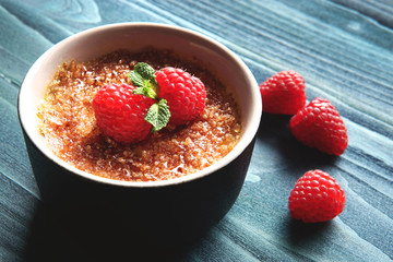  Creme brulee or catalana  with raspberries . Traditional French, Spanish and Italian vanilla cream dessert with caramelized brown sugar. Delicious,  tasty, sweet dish. Copy space. Selective focus