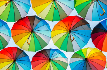 Fototapeta na wymiar a collection of open umbrellas floating in the air, each umbrella is painted in all colors of the rainbow, photographed from below