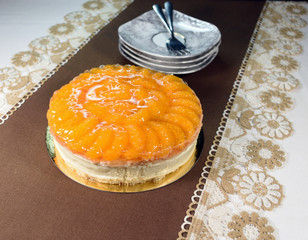 Cheese cake with cream and tangerines. On a white brown background