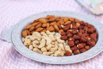 metal plate of different types of nuts on a white tablecloth