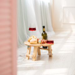 A folding legs tray table is on the bed, red wine in two glasses, blue cheese, camembert, brie, jamon, ciabata, surprise, breakfast in bed, a gift for Valentine's day, birthday, nobody