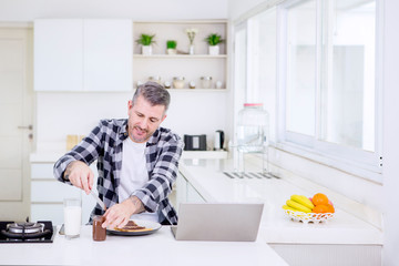 Caucasian man making breakfast while working