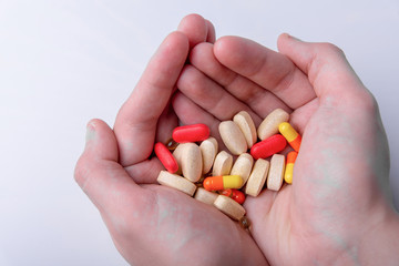 pills and capsules in hand on white background