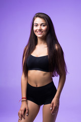 Fototapeta premium Fitness woman with a beautiful body in black lingerie isolated on violet background