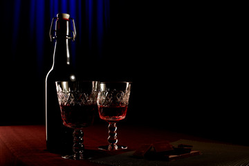Wine bottle with a crystal glass standing on a table. Blue backg