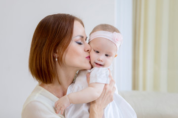 Caucasian woman kissing her baby cheek at home