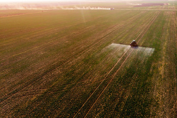 Tractor spraying fertilizer or pesticides on field with sprayer