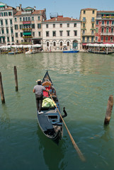 Fototapeta na wymiar Venice, Italy: Gondolier enters his gondola in the Grand Canal nearby Rialto Bridge