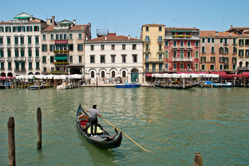Fototapeta na wymiar Venice, Italy: Gondolier enters his gondola in the Grand Canal nearby Rialto Bridge