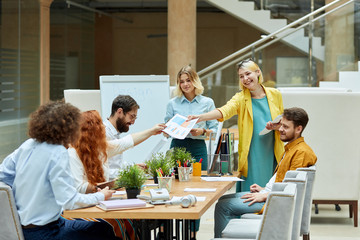 Group of young joyful guys in good mood, disscuss work related issues in roomy modern office. Designers meeting concept