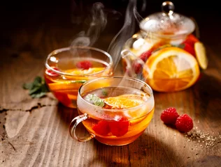 Poster Fruit hete thee met de toevoeging van sinaasappelen, citroenen, mandarijnen en frambozen in een glazen beker op een houten tafel. Gezonde warme drank © zi3000