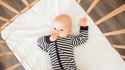 Newborn baby lying in bed in striped clothes
