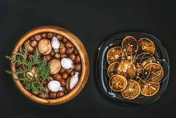 Wooden bowl with nuts, walnuts and hazelnuts. Dish decorated with Christmas baubles and slices of dried oranges