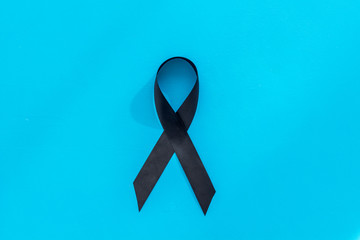 Disease control concept. Black ribbon on blue background top view copy space
