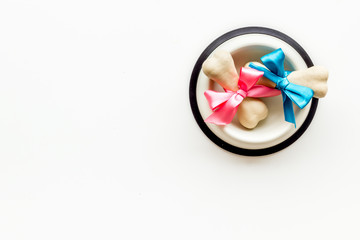 Dog's birthday concept. Chewing bones with bow in bowl on white background top view copy space