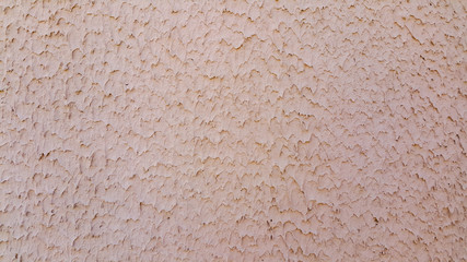 The facade of the building, pink plaster and textured background on the wall, the effect of a landslide.