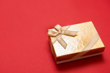 Flat lay of romantic gift decorated with ribbon on red background