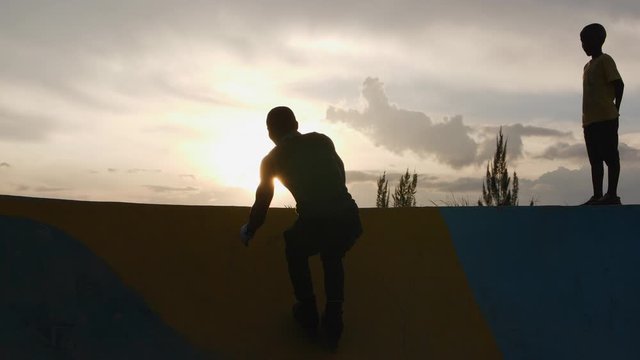 silhouette of rollerblader riding on the ramp towards the sun