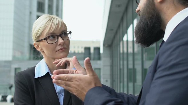 Woman in suit listening to inspired male colleague, discussing perspectives