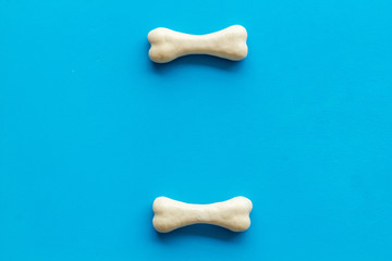 Obraz premium Food and toys for dogs. Chewing bones on blue background top view space for text